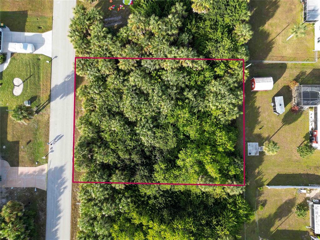 An aerial view shows a rectangular, tree-covered vacant lot outlined in pink next to a road — 18699 ASHCROFT CIRCLE, PORT CHARLOTTE, FL