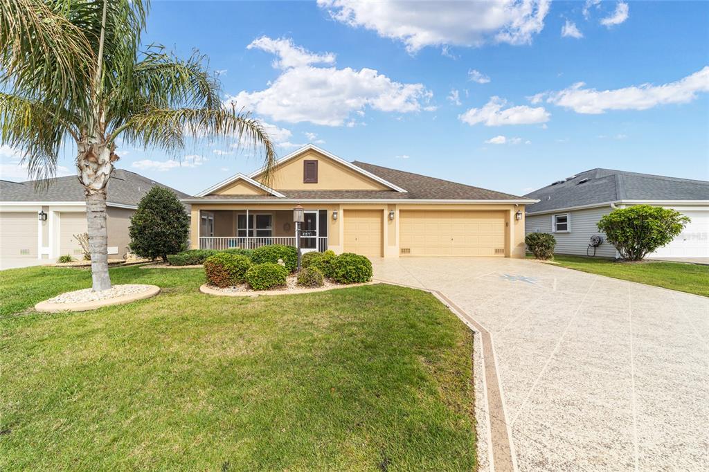 A single-story house with a tan exterior, a three-car garage, and a palm tree — 481 ISLAND HOUSE PATH, THE VILLAGES, FL