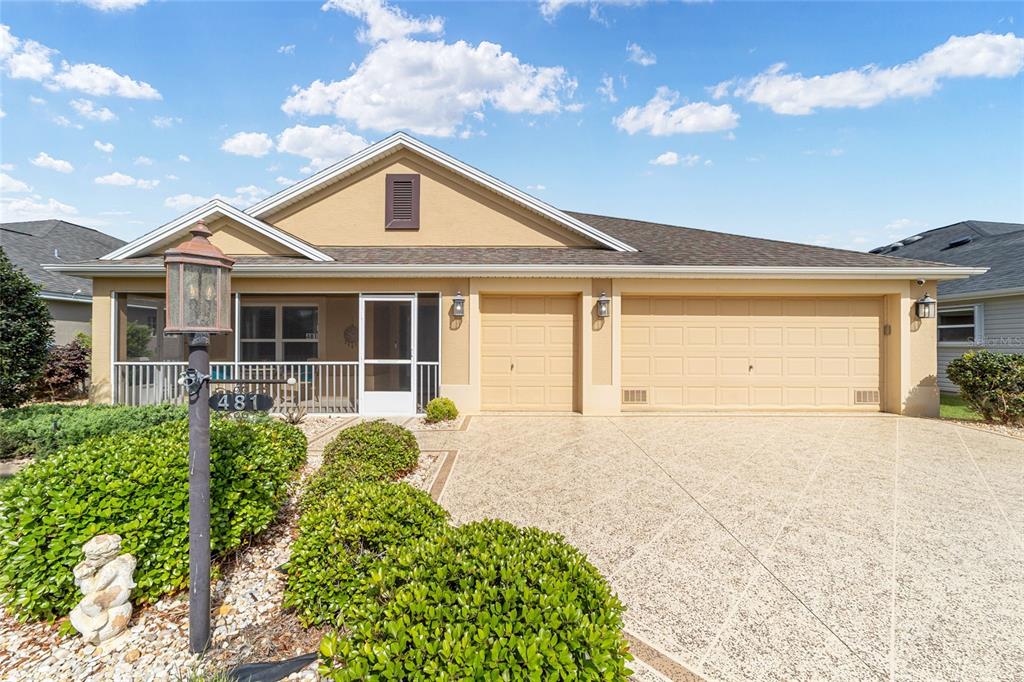 A single-story house with a tan exterior, a screened-in porch, and a three-car garage — 481 ISLAND HOUSE PATH, THE VILLAGES, FL