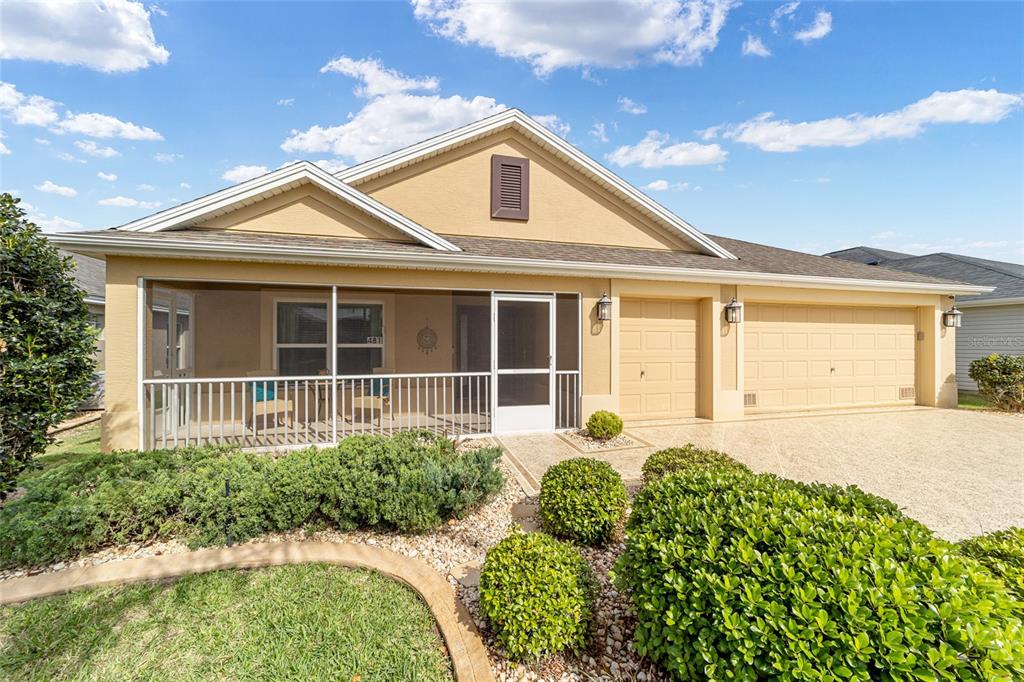 A single-story house with a tan stucco exterior, a screened front porch, and a garage — 481 ISLAND HOUSE PATH, THE VILLAGES, FL