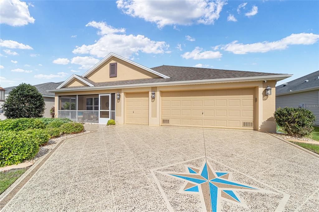 A single-story house with a tan exterior, a screened porch, and a decorative concrete driveway — 481 ISLAND HOUSE PATH, THE VILLAGES, FL