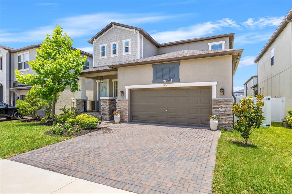 A two-story suburban house features a stone-accented facade, a paved driveway, and a garage — 7706 S JUANITA STREET, TAMPA, FL