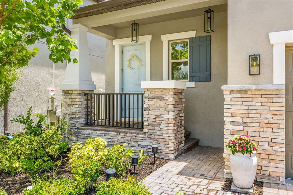 A front porch with stone pillars, a light blue door, and a brick walkway — 7706 S JUANITA STREET, TAMPA, FL