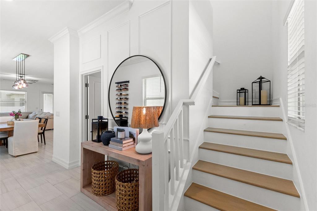 A foyer features a wooden console table, a round mirror, and stairs with wooden treads — 7706 S JUANITA STREET, TAMPA, FL