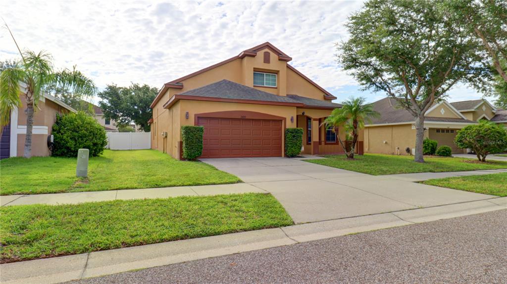 A two-story tan house with a two-car garage and a paved driveway — 13659 ARTESA BELL DRIVE, RIVERVIEW, FL