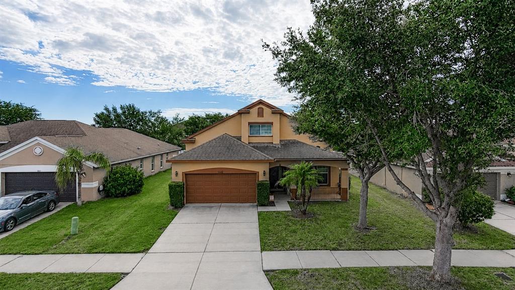 An exterior view of a two-story suburban house with a driveway and a front lawn — 13659 ARTESA BELL DRIVE, RIVERVIEW, FL