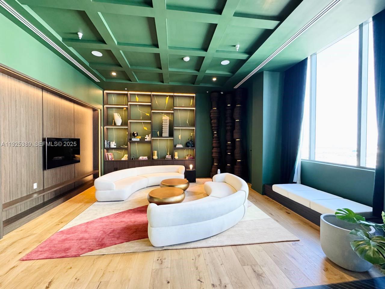 A modern living room features green coffered ceilings, curved white sofas, and built-in shelving — 11 NE 6th # 2813, Miami FL 33132, MIAMI, FL