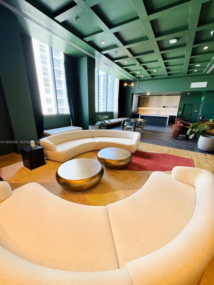 A modern lounge features curved white sofas, gold coffee tables, and a coffered green ceiling — 11 NE 6th # 2813, Miami FL 33132, MIAMI, FL