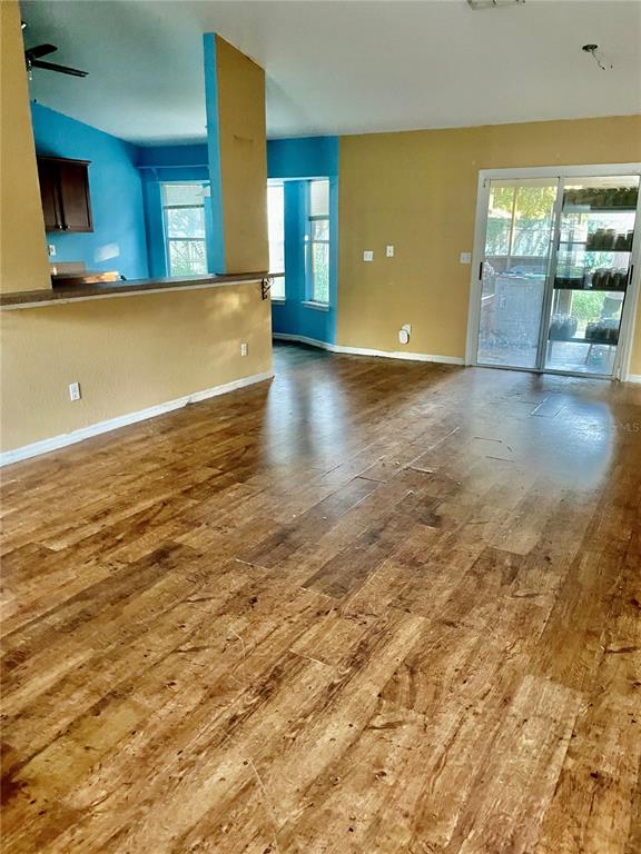 A living area with wood-look flooring, tan walls, and a blue-accented kitchen pass-through — 2 REDWOOD TRACK RUN, OCALA, FL