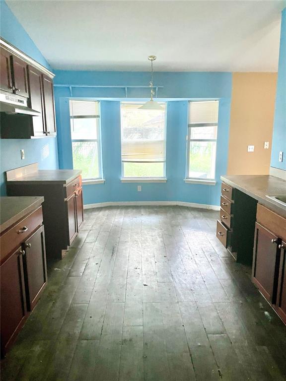 A kitchen with dark wood cabinets, blue walls, and wood-look flooring features a bay window — 2 REDWOOD TRACK RUN, OCALA, FL