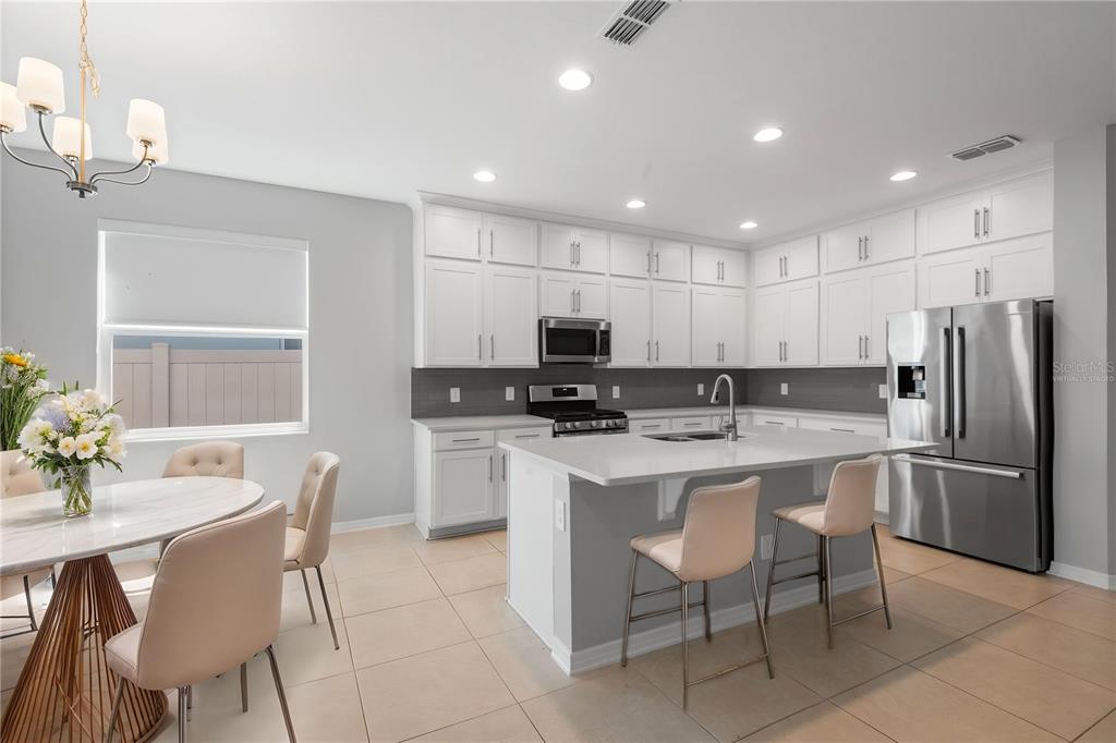 A kitchen with white cabinets, a central island, stainless steel appliances, and an adjacent dining area — 2017 BOSS HEWETT STREET, OAKLAND, FL