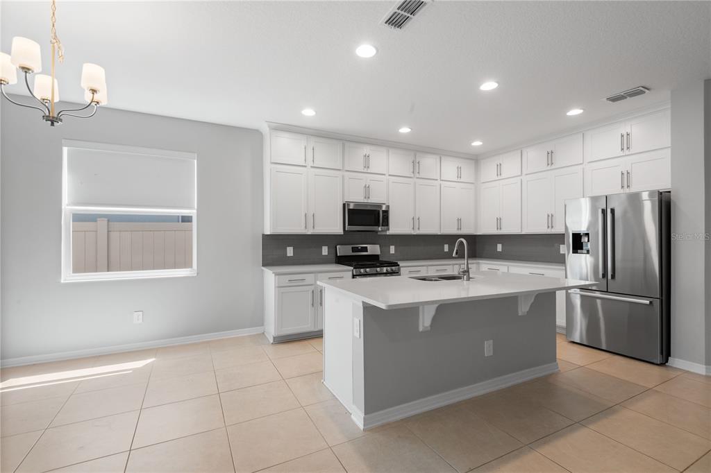 A modern kitchen features white cabinetry, stainless steel appliances, a center island, and tile flooring — 2017 BOSS HEWETT STREET, OAKLAND, FL