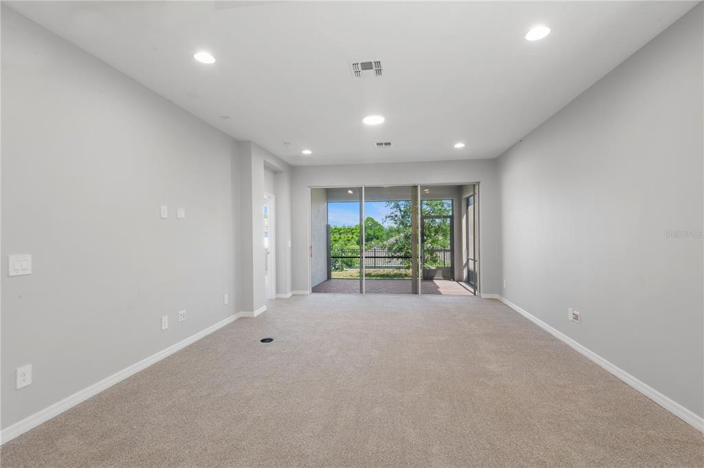 A spacious living room with neutral carpet, light gray walls, recessed lighting, and a sliding door — 2017 BOSS HEWETT STREET, OAKLAND, FL