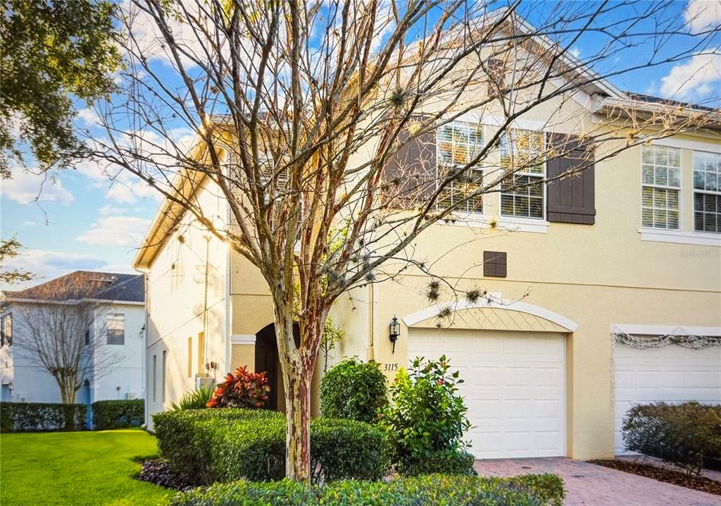 A two-story tan townhouse with a white garage door and brown shutters — 3115 CAPRI ISLE WAY, ORLANDO, FL