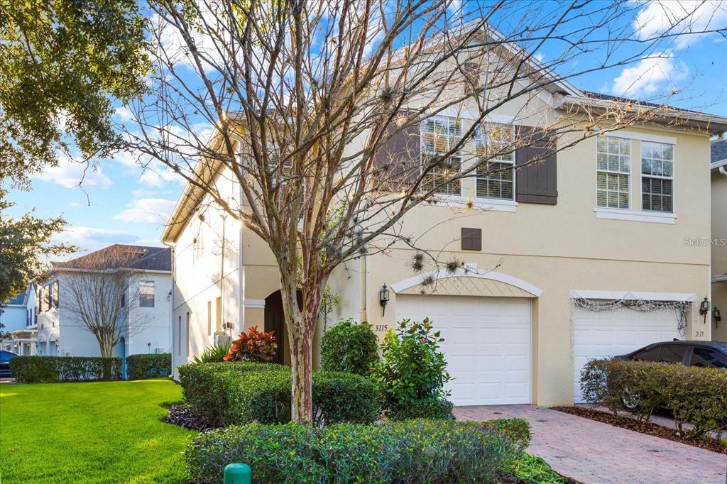 A two-story house with a beige stucco exterior, a white garage door, and dark shutters — 3115 CAPRI ISLE WAY, ORLANDO, FL