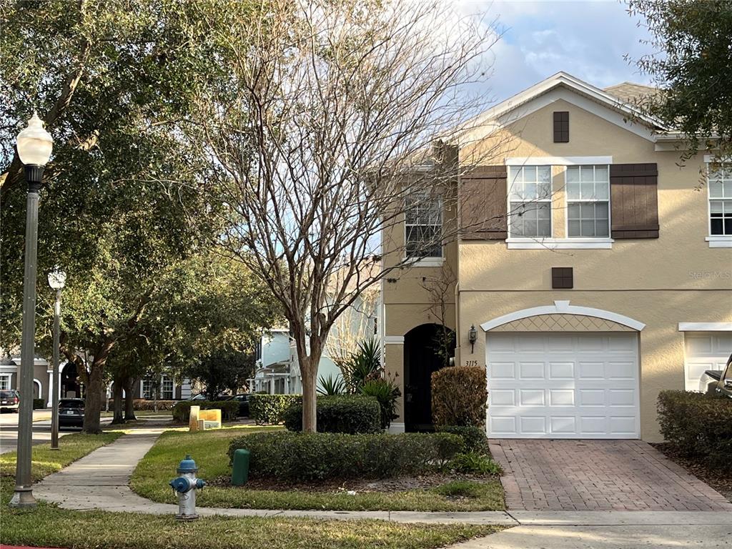 A two-story townhouse with a beige stucco exterior, a single-car garage, and a bare tree — 3115 CAPRI ISLE WAY, ORLANDO, FL