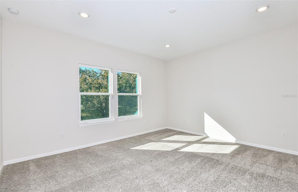 An open-concept living area with light wood-look flooring, white walls, and a kitchen island — 1361 ALLAGASH DRIVE, ZEPHYRHILLS, FL