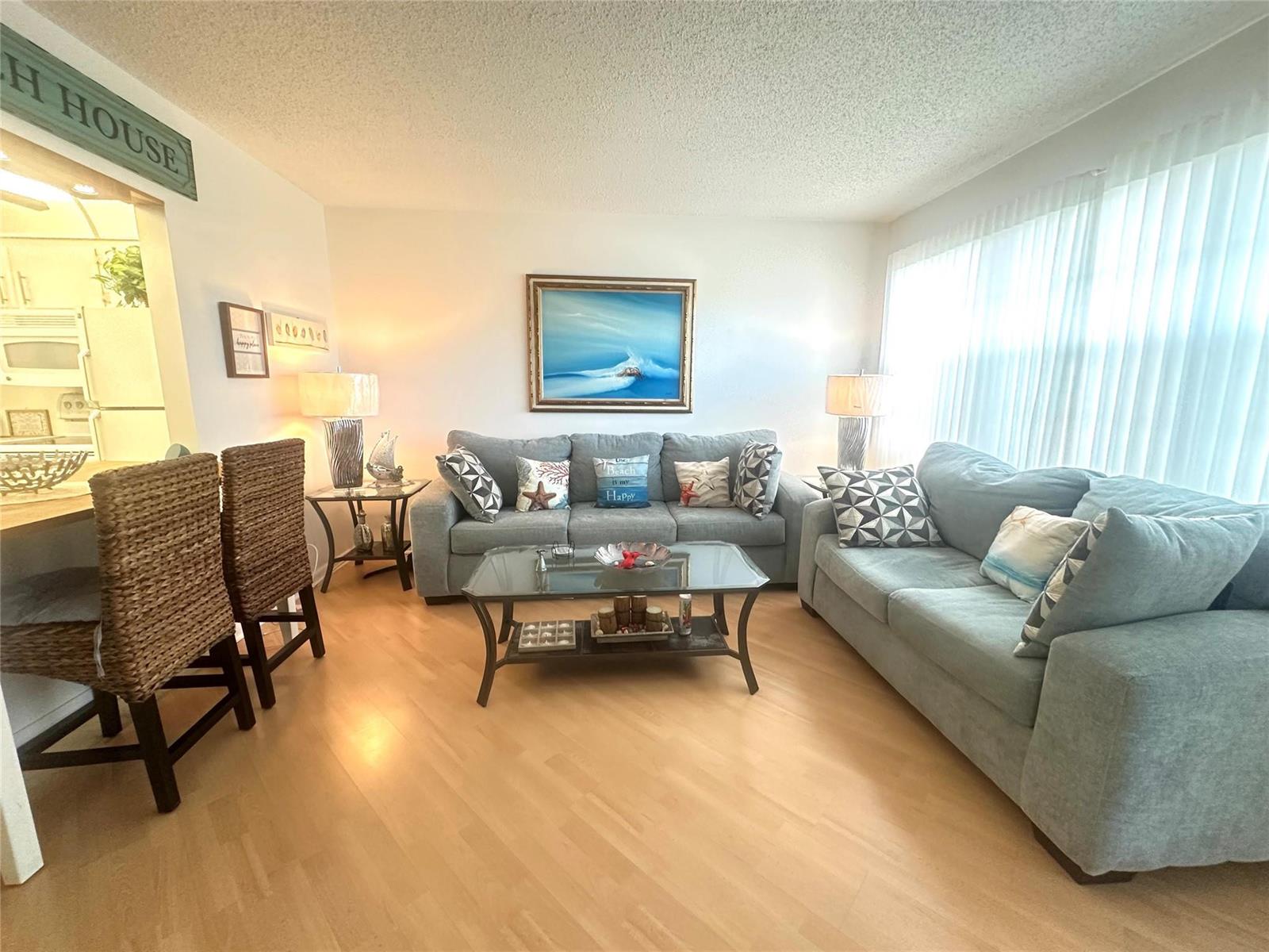 A living room features two gray sofas, a glass coffee table, and light wood flooring — 2004 Harwood C # 2004, Deerfield Beach FL 33442, DEERFIELD BEACH, FL