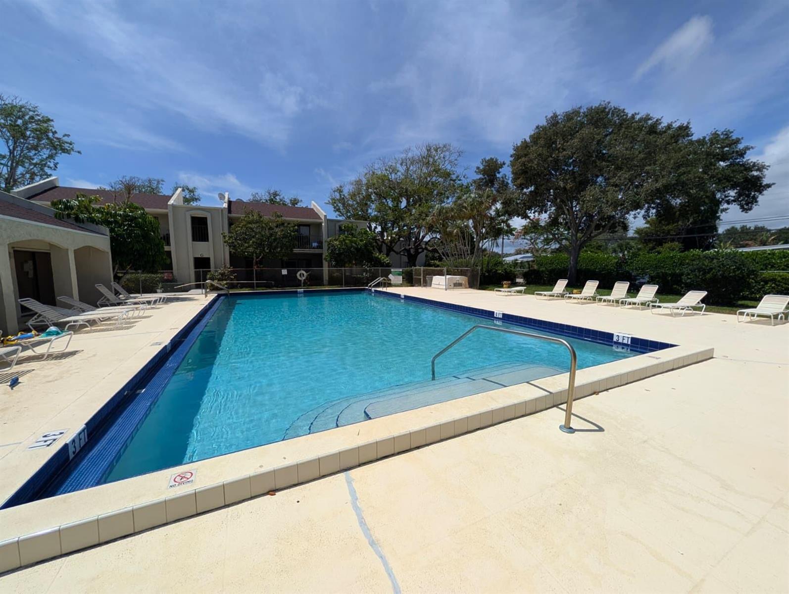 An outdoor swimming pool with lounge chairs on a concrete deck near a residential building — 150 Pineview Road Apt E6, Jupiter FL 33469, JUPITER, FL