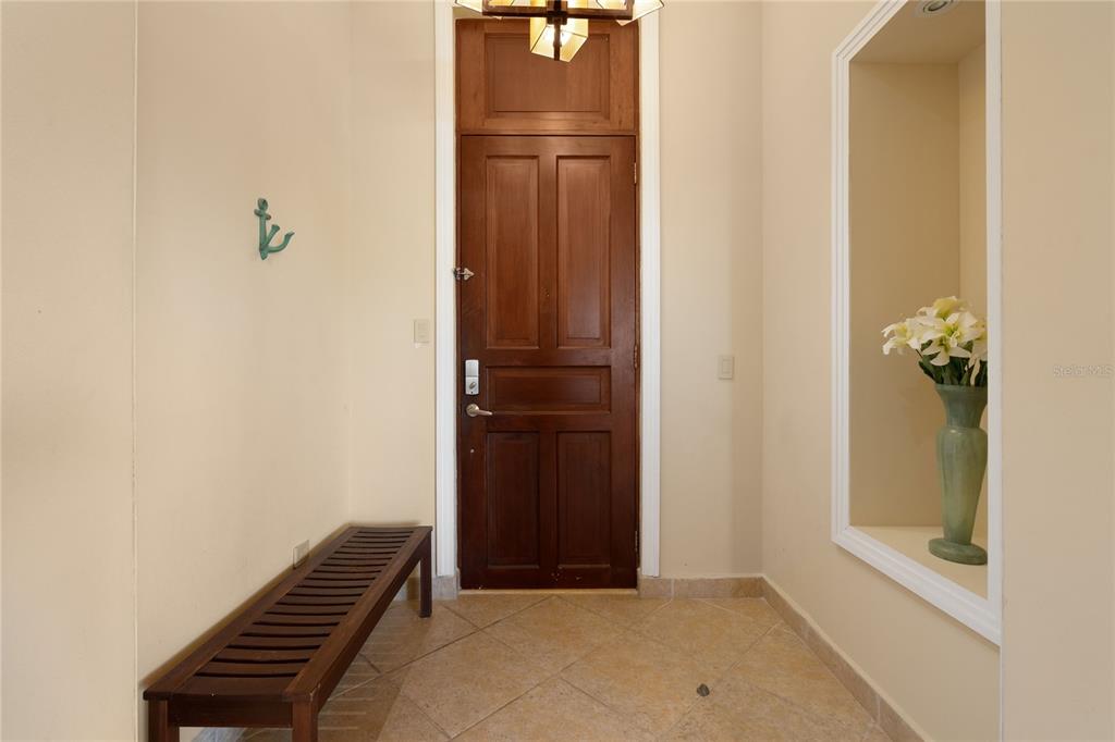 An entryway features a wooden door, a bench, and a recessed wall niche with flowers — 500 OCEAN DRIVE UNIT 553, HUMACAO, PR