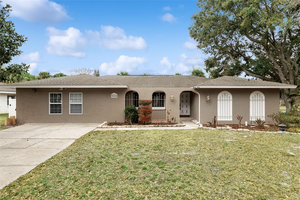 A single-story house with a brown stucco exterior, arched windows, and a concrete driveway — 6246 SILVER GLEN COURT, ORLANDO, FL
