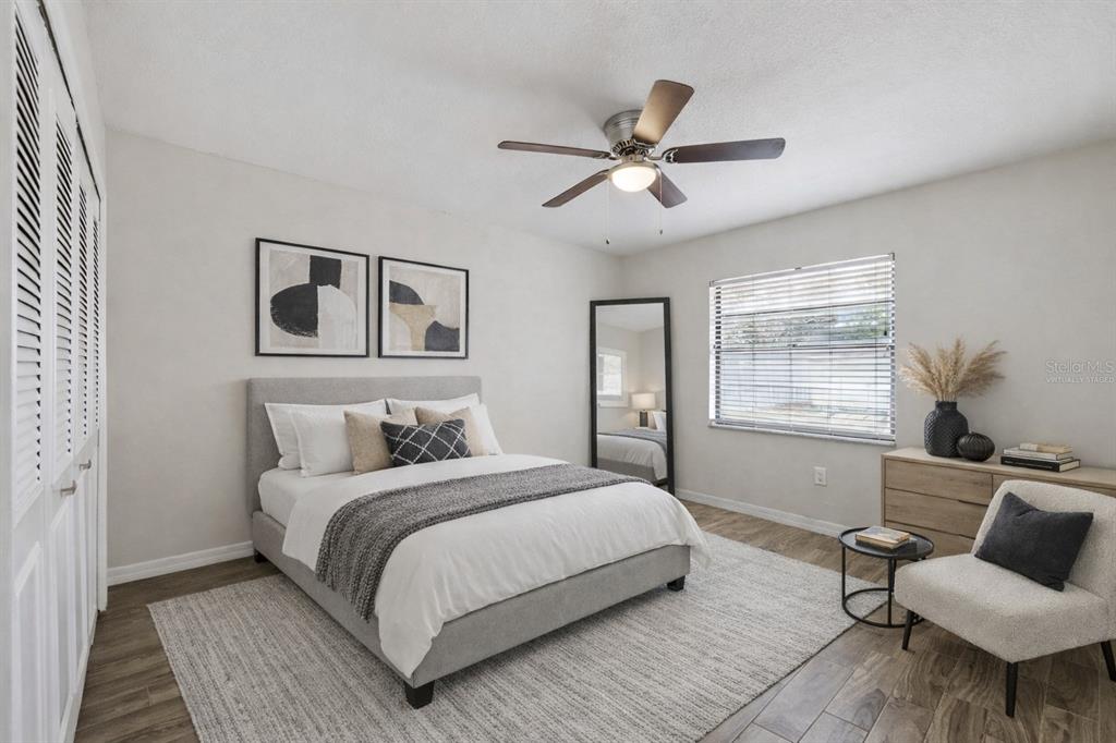 A bedroom features a gray upholstered bed, a ceiling fan, a floor mirror, and wood-look flooring — 6246 SILVER GLEN COURT, ORLANDO, FL