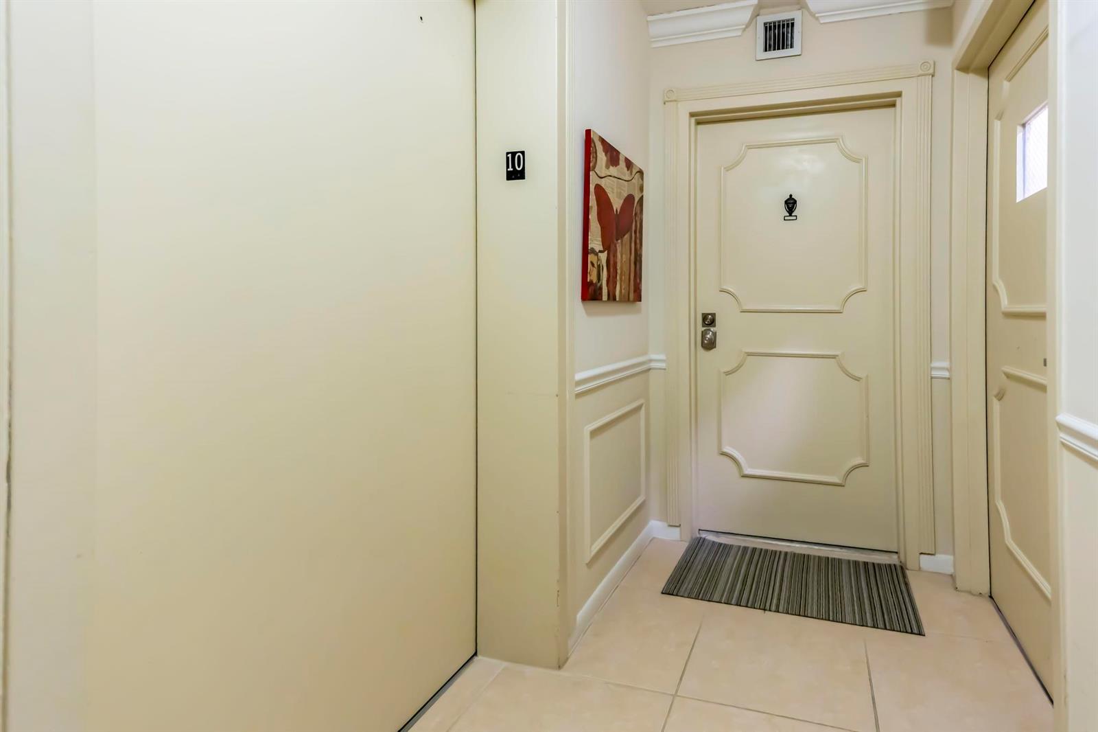 A hallway features a numbered door, a decorative painting, and a striped floor mat — 4301 N Ocean Boulevard # 1002, Boca Raton FL 33431, BOCA RATON, FL