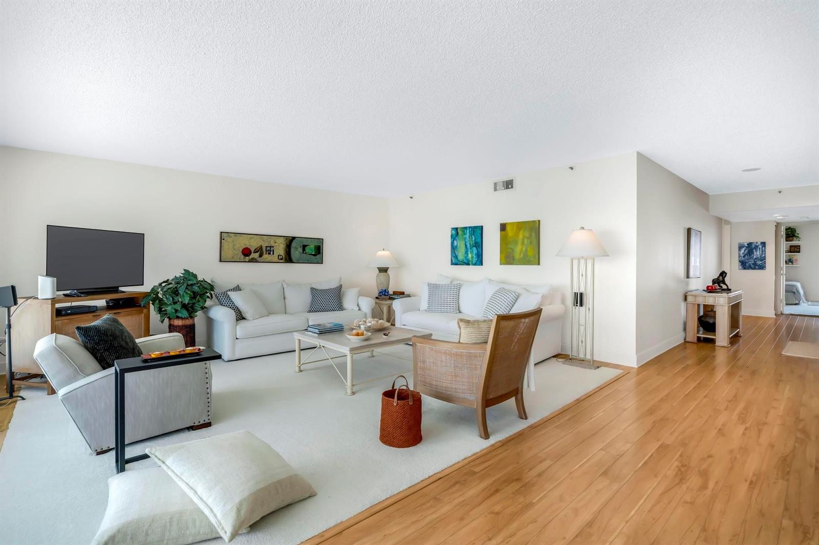 A bright living room features white sofas, a wooden armchair, and light hardwood flooring — 4301 N Ocean Boulevard # 1002, Boca Raton FL 33431, BOCA RATON, FL