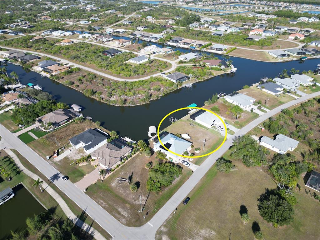 An aerial view shows a waterfront house with a large yard and a boat dock — 8050 ARLEWOOD CIRCLE, PORT CHARLOTTE, FL