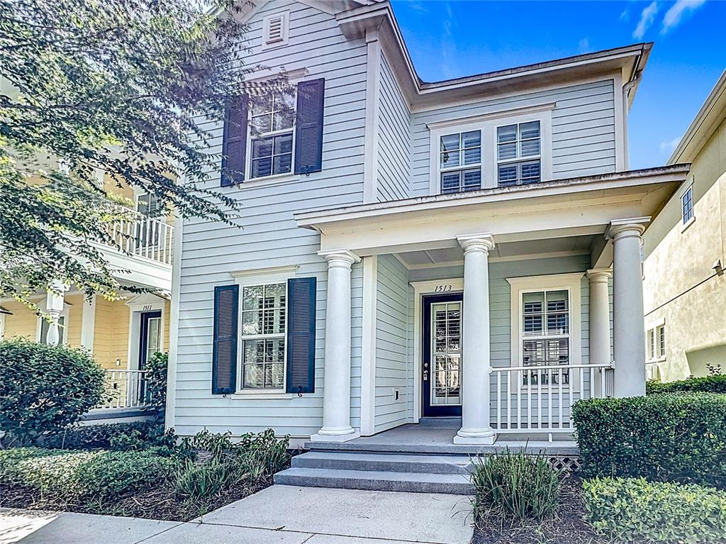 A light blue two-story house features a front porch with white columns and shutters — 1513 RESOLUTE STREET, CELEBRATION, FL
