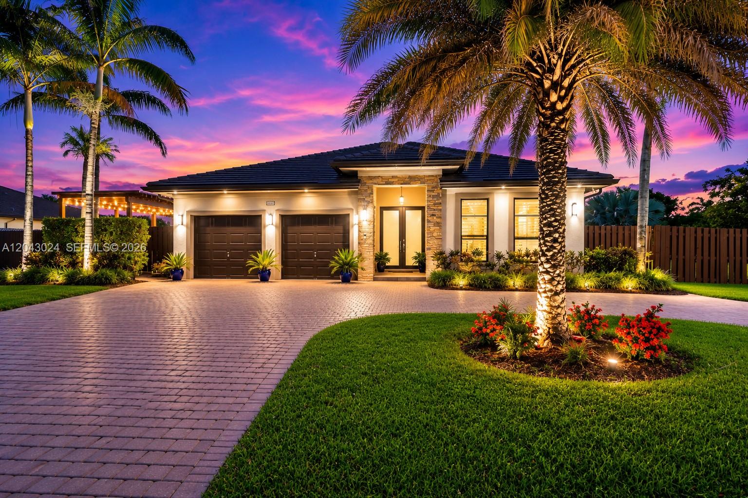 A single-story house with a two-car garage, stone accents, and palm trees at twilight — 21365 SW 177th Ct, Miami FL 33187, MIAMI, FL
