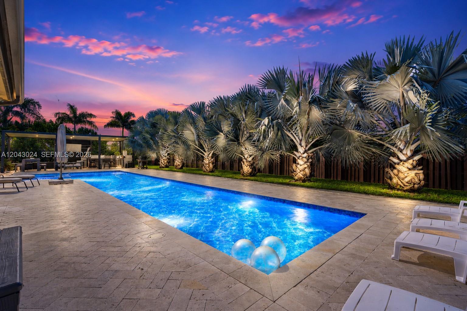 A rectangular swimming pool is surrounded by a stone patio and a row of palm trees — 21365 SW 177th Ct, Miami FL 33187, MIAMI, FL