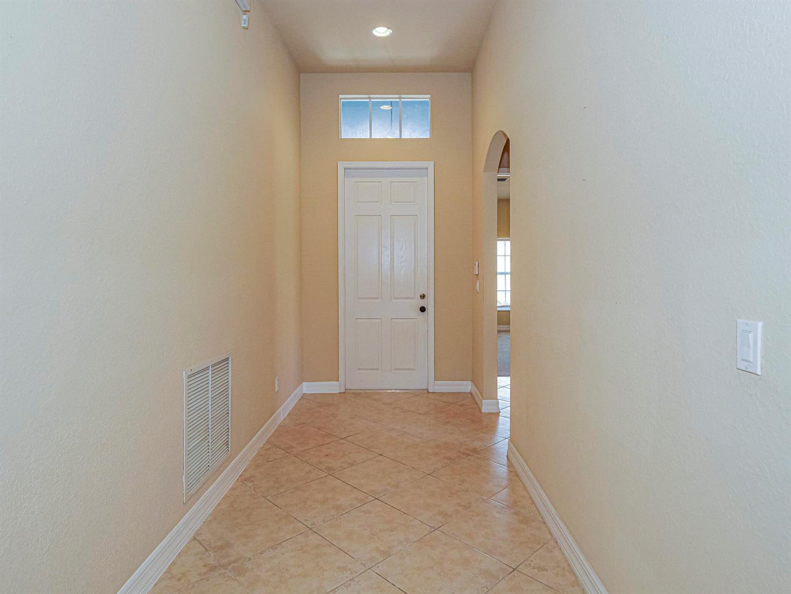 A tiled entryway features a white front door, a transom window, and an arched opening — 5561 57th Way, Vero Beach FL 32967, VERO BEACH, FL