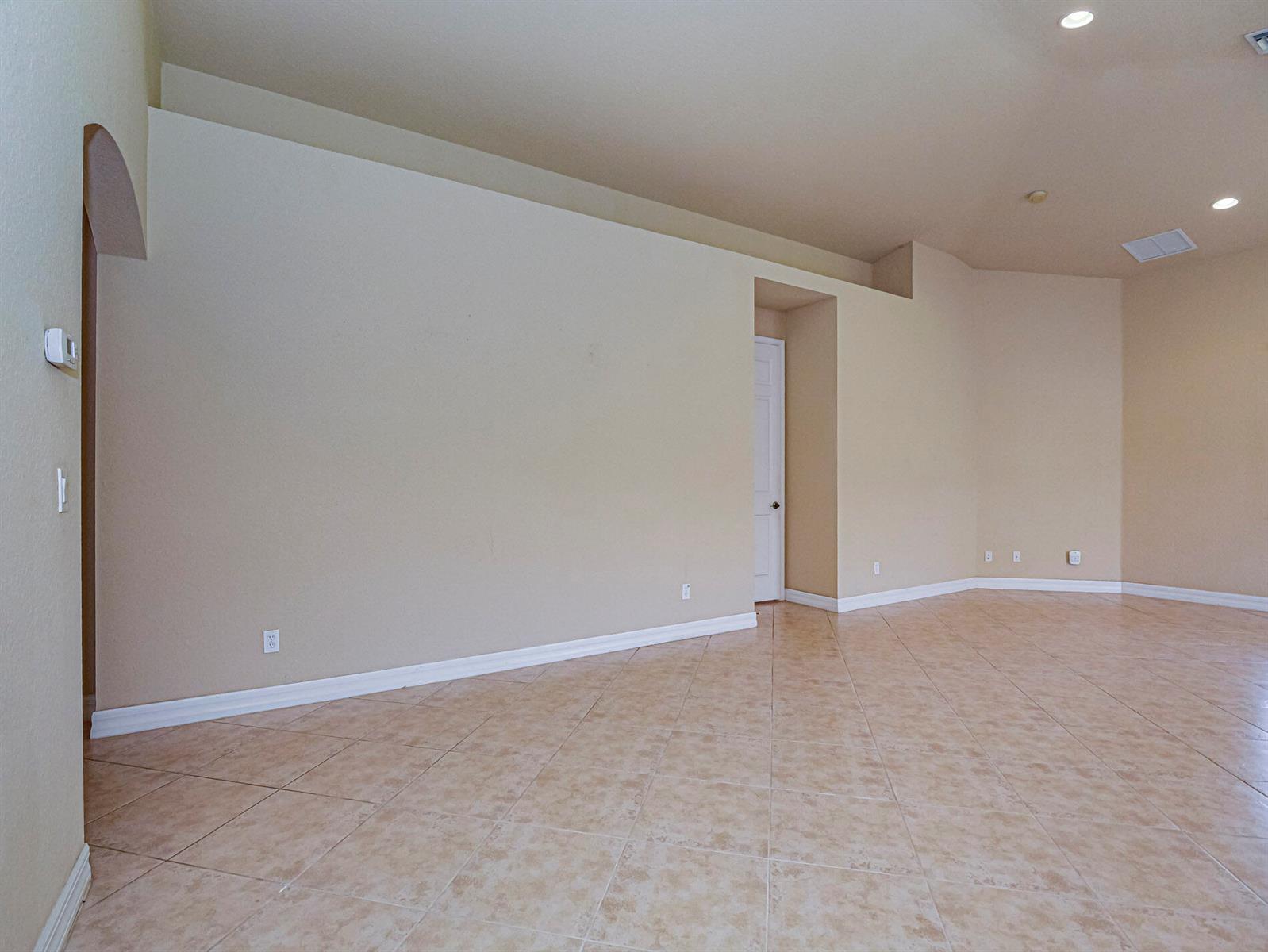 An empty room with beige walls, tile flooring, and a recessed doorway — 5561 57th Way, Vero Beach FL 32967, VERO BEACH, FL