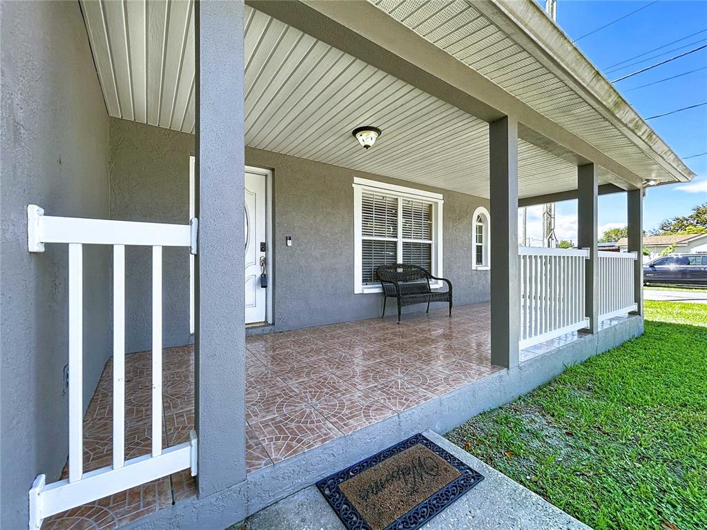 A covered front porch features tiled flooring, white railings, and a black bench — 3324 W ABDELLA STREET, TAMPA, FL
