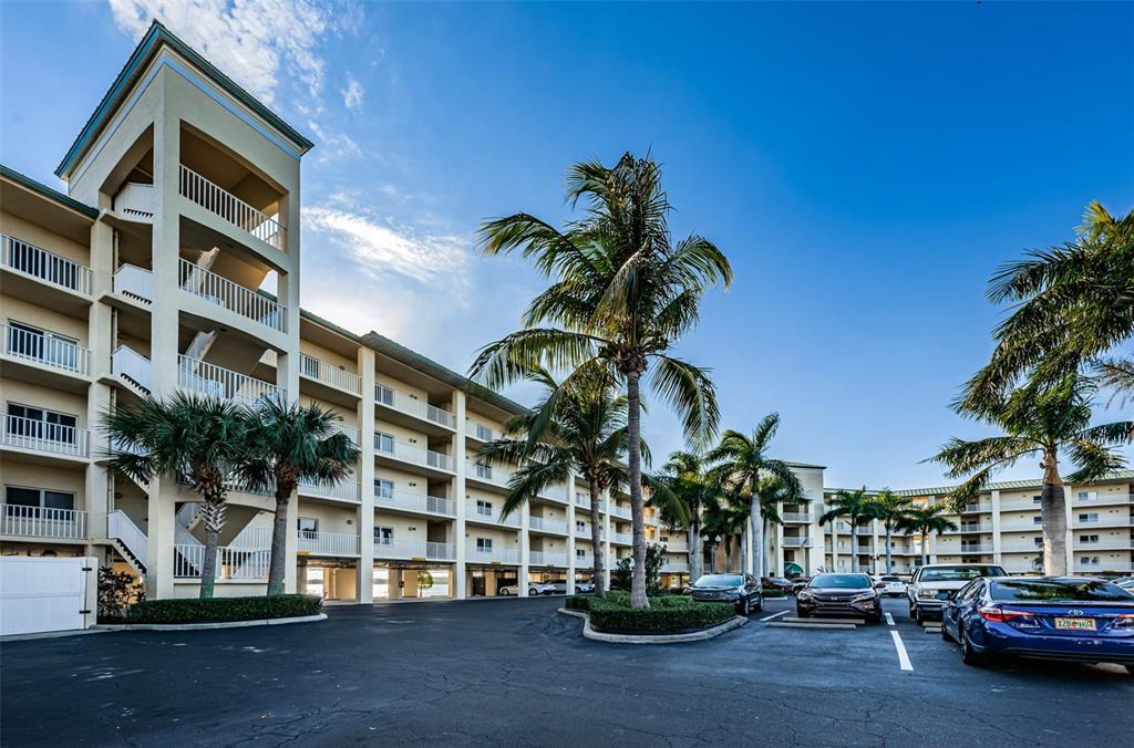 A multi-story apartment building with balconies and palm trees in a parking lot — 8800 BAY PINES BOULEVARD UNIT 303, ST PETERSBURG, FL