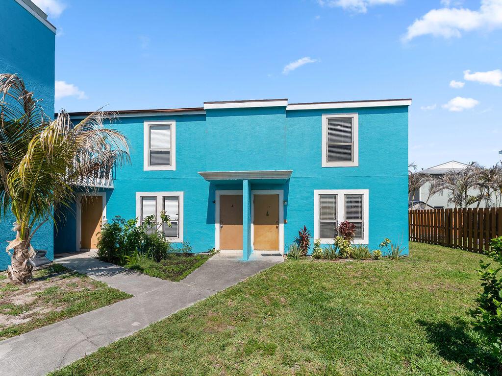 A two-story, bright blue apartment building features tan doors and a concrete walkway — 642 Eldorado Street, Fort Pierce FL 34949, FORT PIERCE, FL