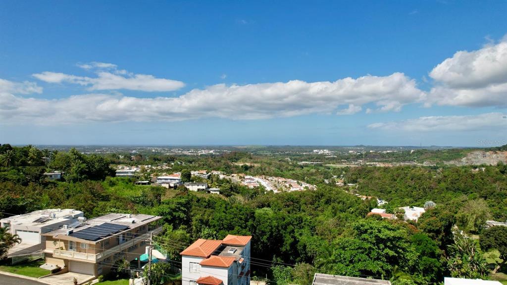 An elevated view of a residential neighborhood surrounded by dense green hills and trees — 3 CALLE CAGUAX, CAROLINA, PR