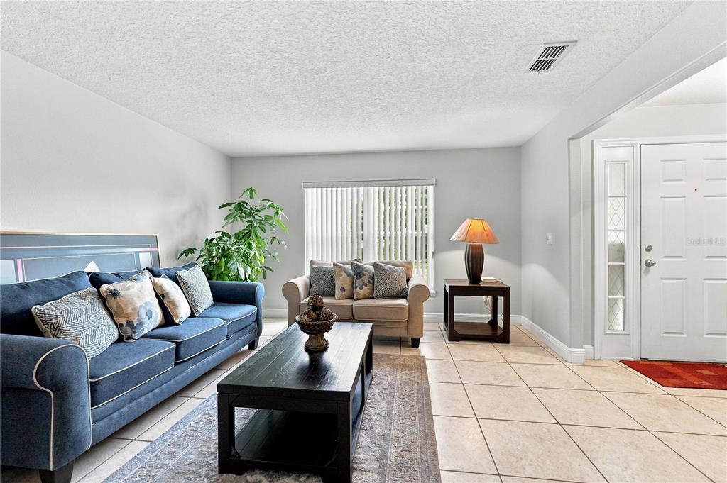 A living room features a blue sofa, a beige loveseat, a coffee table, and tile flooring — 2512 ABACUS COURT, LAKE MARY, FL