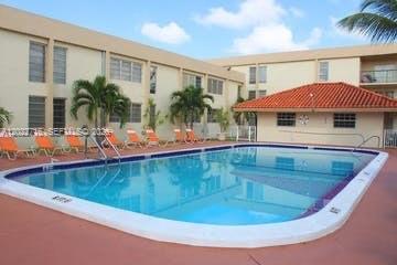 A swimming pool sits in the courtyard of a multi-story apartment building with palm trees — HIALEAH, FL