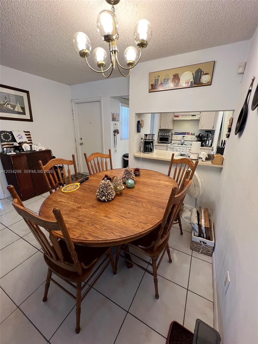 A dining area features a wooden table with chairs, tile flooring, and a kitchen pass-through — 9710 Hammocks Blvd # 31, Miami FL 33196, MIAMI, FL