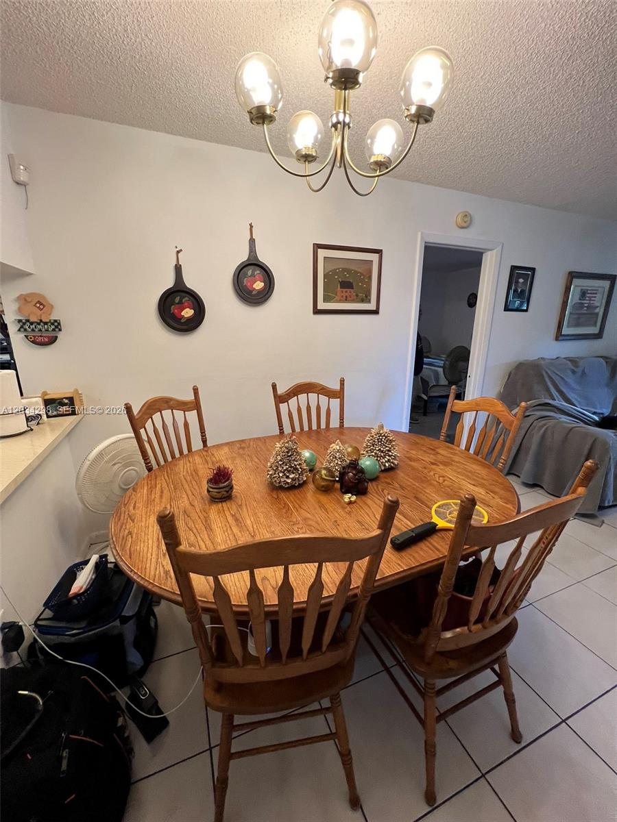 A dining room features a wooden table with chairs, a chandelier, and wall decor — 9710 Hammocks Blvd # 31, Miami FL 33196, MIAMI, FL