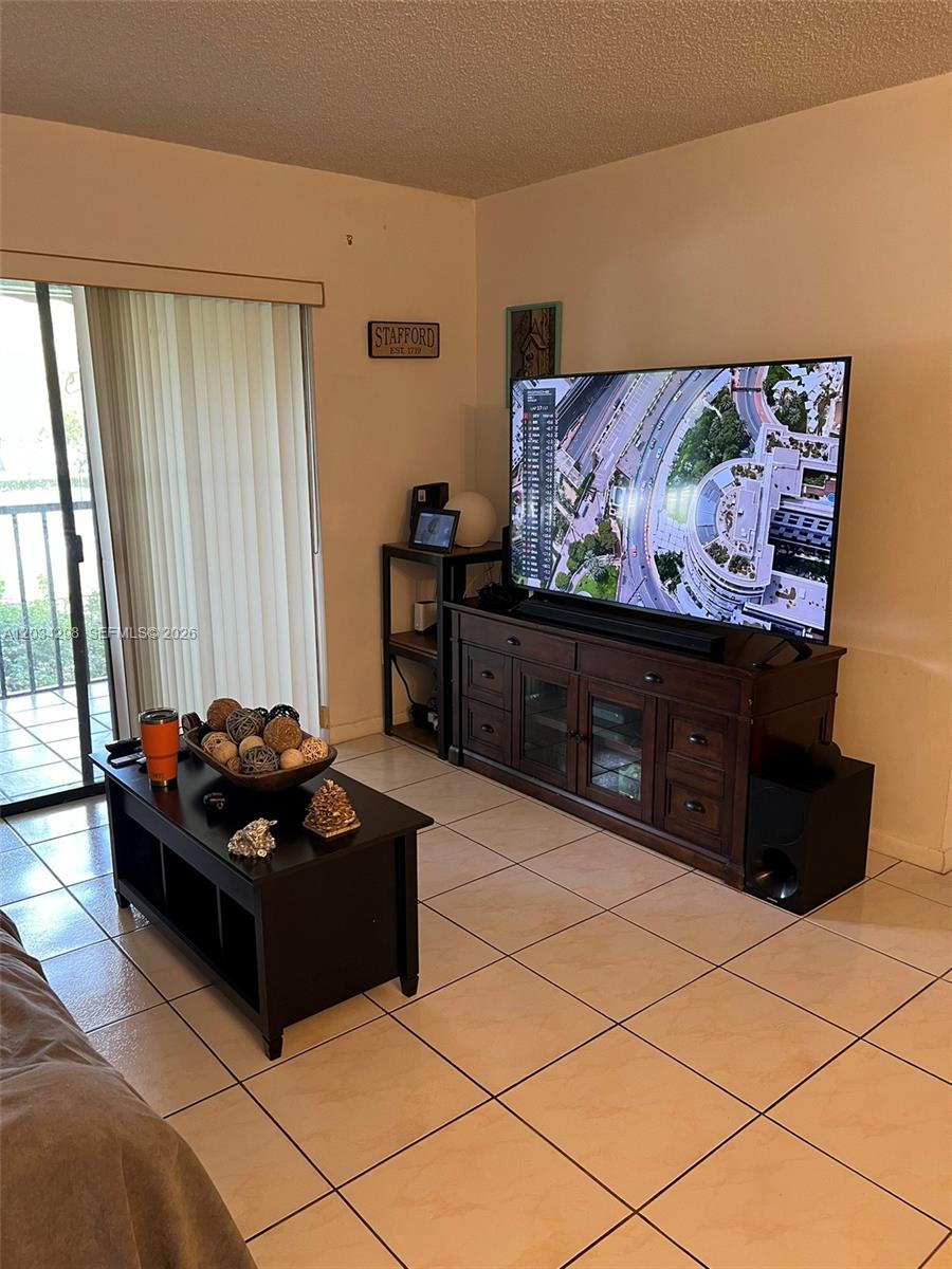A living room features a large television on a wooden console, tile flooring, and a balcony — 9710 Hammocks Blvd # 31, Miami FL 33196, MIAMI, FL