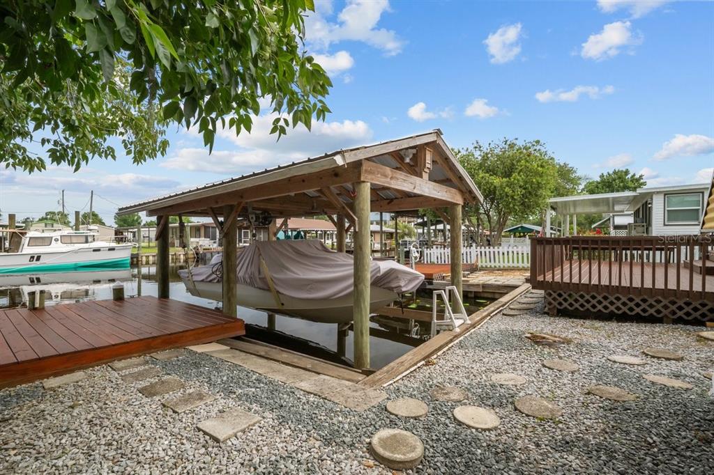 A covered boat lift sits beside a wooden deck and a gravel yard with pavers — 41 SCOTT STREET, WELAKA, FL