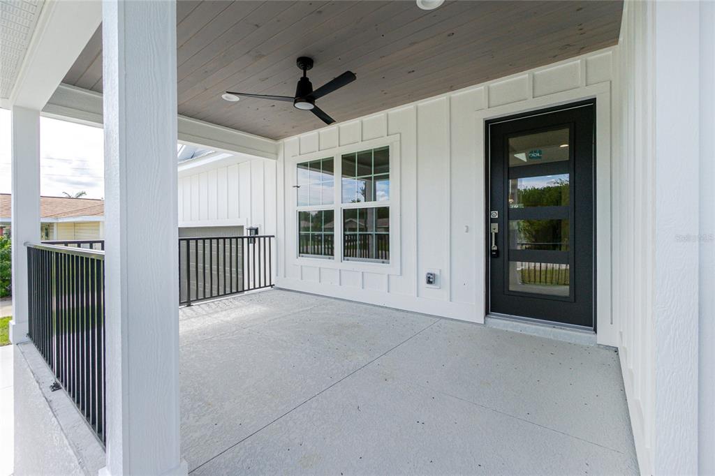 A covered porch features a black front door, a ceiling fan, and white board-and-batten siding — 323 BOCA GRANDE BOULEVARD, PUNTA GORDA, FL