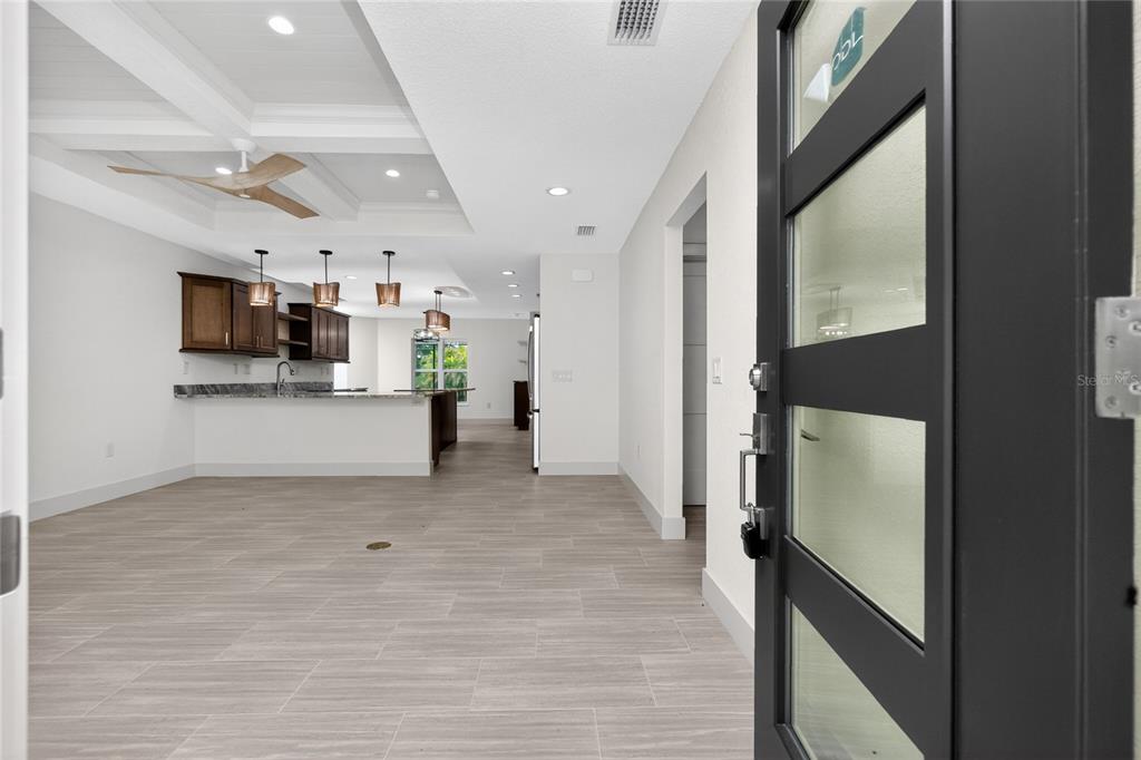 An open-concept kitchen and living area with wood-look tile flooring and a coffered ceiling — 323 BOCA GRANDE BOULEVARD, PUNTA GORDA, FL