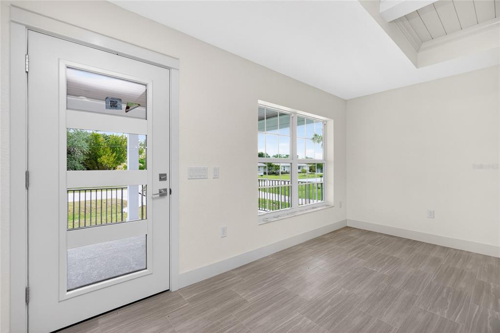 A bright room with light-colored walls, wood-look tile flooring, a window, and a glass-paneled door — 323 BOCA GRANDE BOULEVARD, PUNTA GORDA, FL
