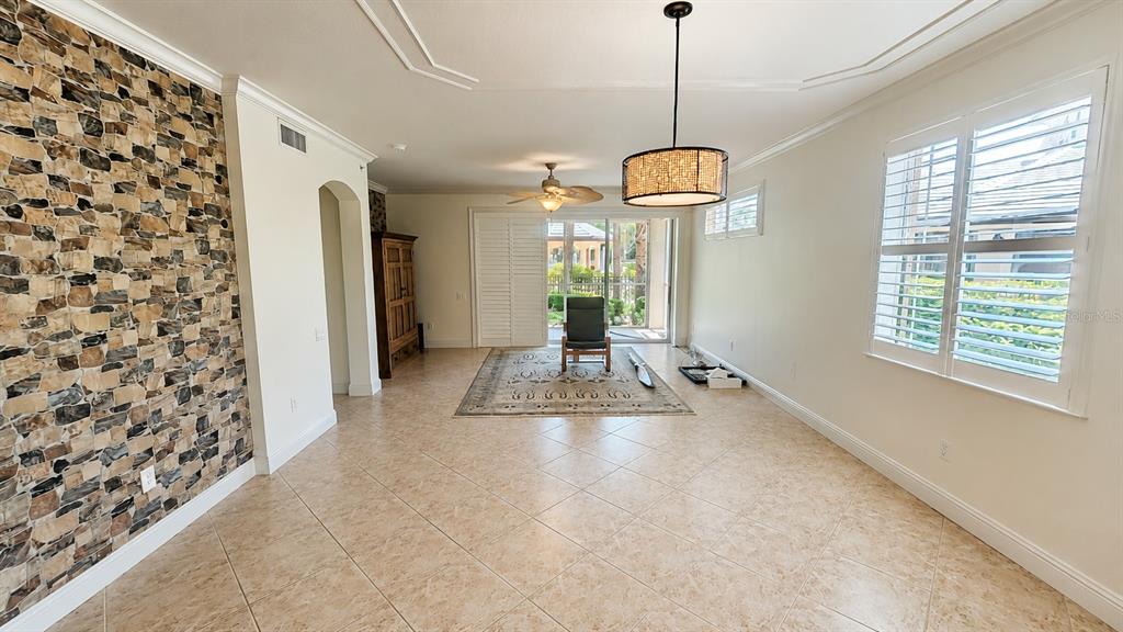 A living room features a stone accent wall, tile flooring, and a sliding glass door — 6552 MOORINGS POINT CIRCLE UNIT 102, LAKEWOOD RANCH, FL