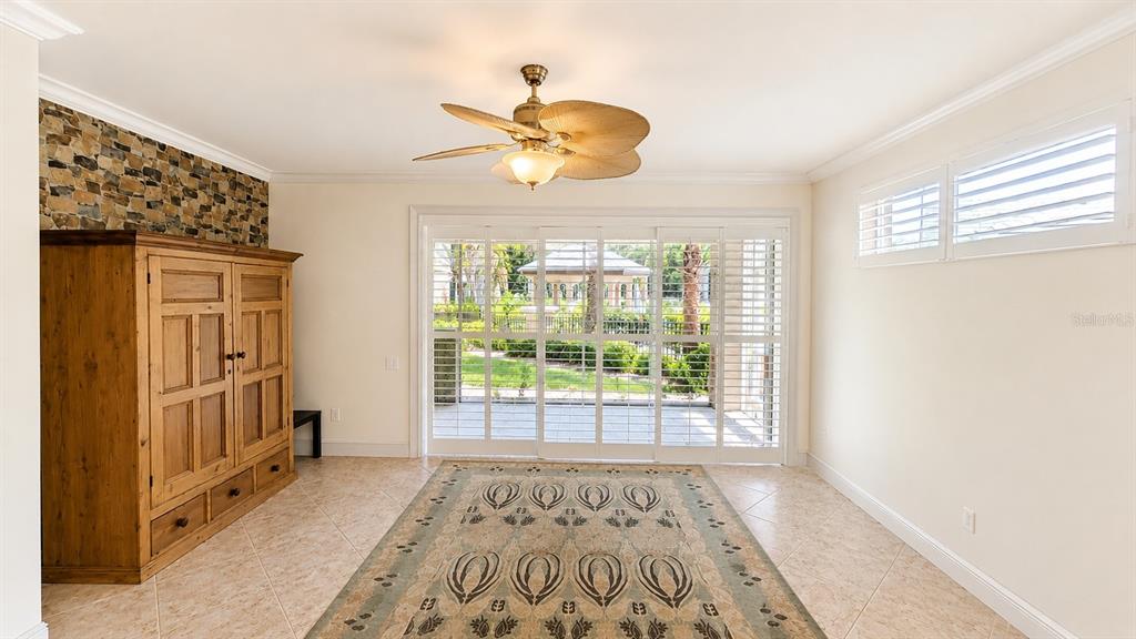 A room with tile floors, a ceiling fan, a wooden armoire, and sliding glass doors — 6552 MOORINGS POINT CIRCLE UNIT 102, LAKEWOOD RANCH, FL