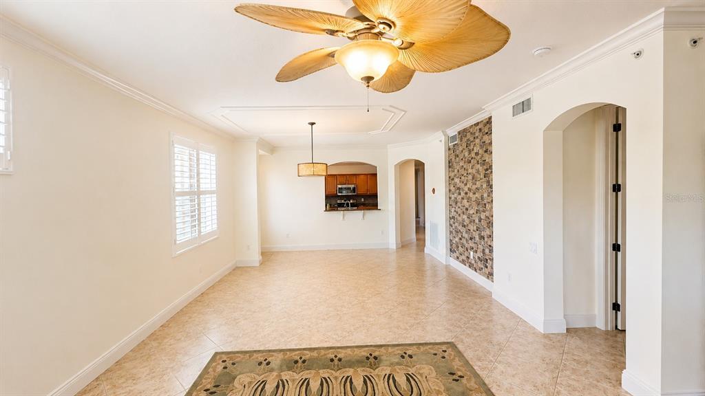 A living and dining area features tile flooring, a ceiling fan, and a stone accent wall — 6552 MOORINGS POINT CIRCLE UNIT 102, LAKEWOOD RANCH, FL